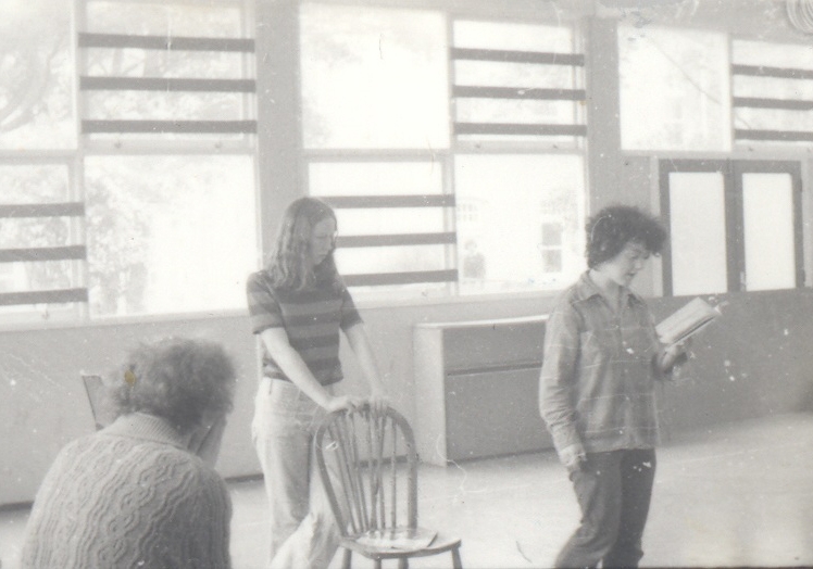 A black-and-white photo of Mick Lally with his back to the camera, Marie Mullen standing behind a chair, and Garry Hynes with a script in her hand