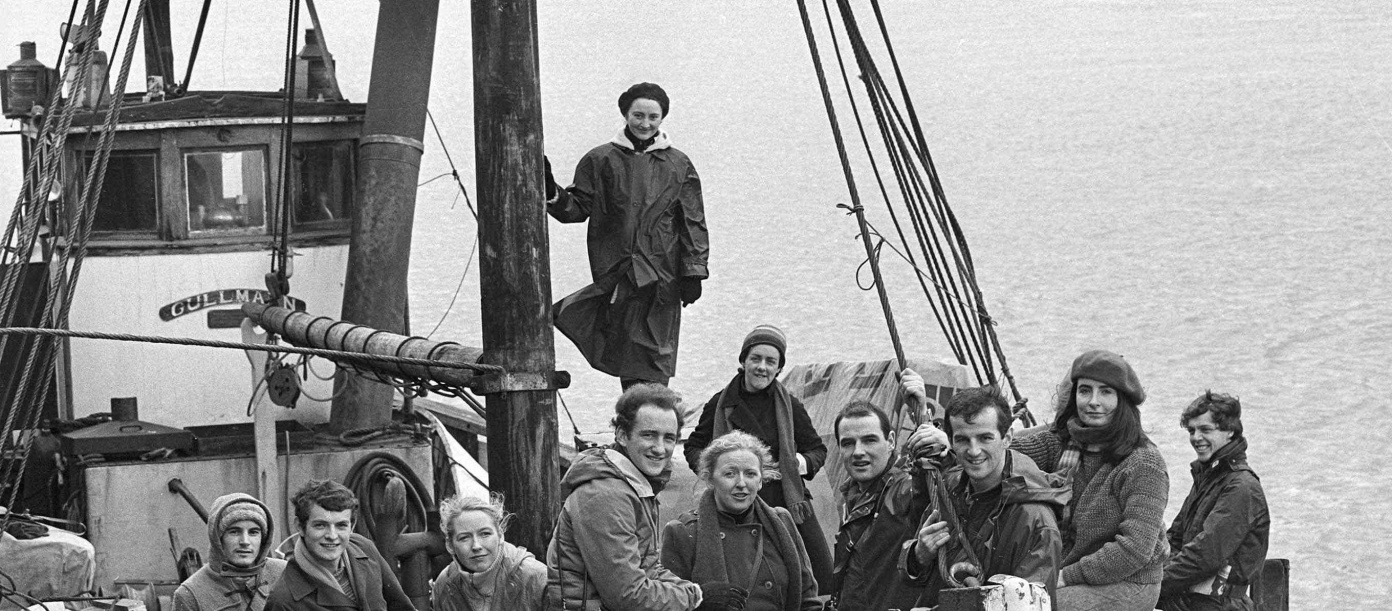 A black-and-white photograph of a large group of people onboard a ship.