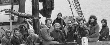 A black-and-white photograph of a large group of people onboard a ship.