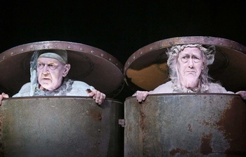 A black-and-white photograph of two people in trash cans with the lids on top of their heads.