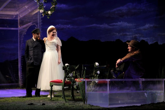 A production photo from The Colleen Bawn featuring Ronan Leahy, Aisling O'Sullivan (in a white wedding dress) and Rory Nolan.