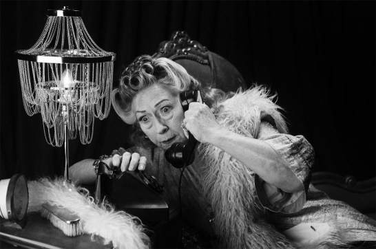 A black-and-white promotional photo of Marie Mullen in Sorry, Wrong Number by Lucille Fletcher. She's seated and using a telephone. There's a concerned look on her face.