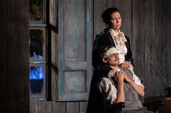A production photo of The Seagull featuring Jack Gleeson seated with his head wrapped in bandages, and Eileen Walsh standing behind him.
