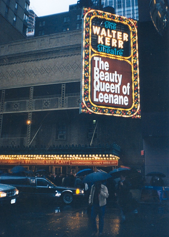 A photo on a rainy day across the street from the Walter Kerr Theatre on Broadway in New York. On the front of the theatre is a large sign advertising The Beauty Queen of Leenane by Martin McDonagh.