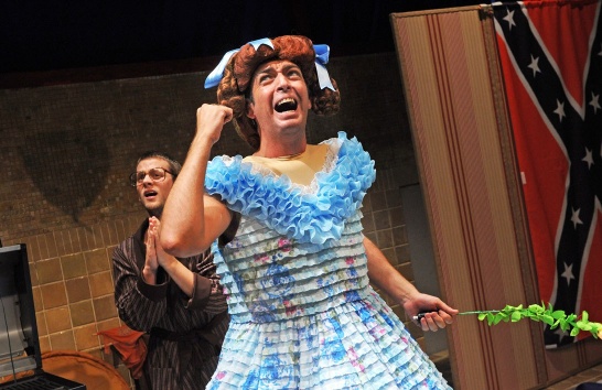 A production photo from Penelope featuring Karl Shiels in a blue dress and red wig.