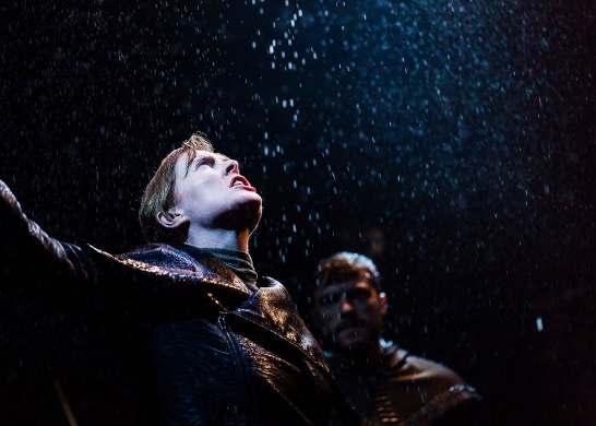 A production photo from DruidShakespeare featuring actors Aisling O'Sullivan and Gavin Drea, there is rain falling on Aisling's upturned face.