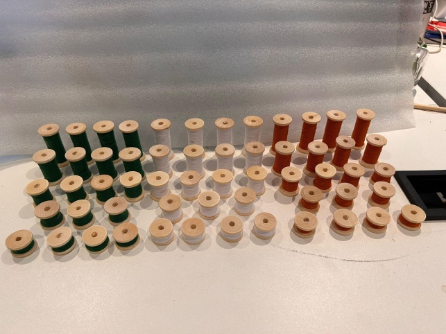 			Spools of green, white and orange thread