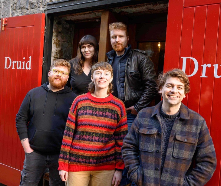 Five people pose together outside The Mick Lally Theatre on Druid Lane.