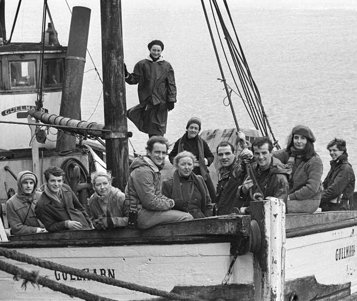 A black-and-white photograph of a large group of people onboard a ship.