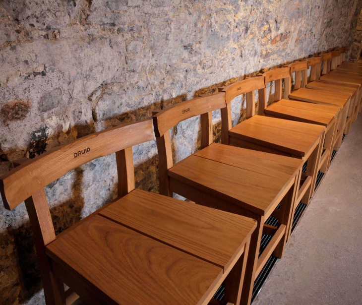 A row of wooden chairs lined up together against a wall.