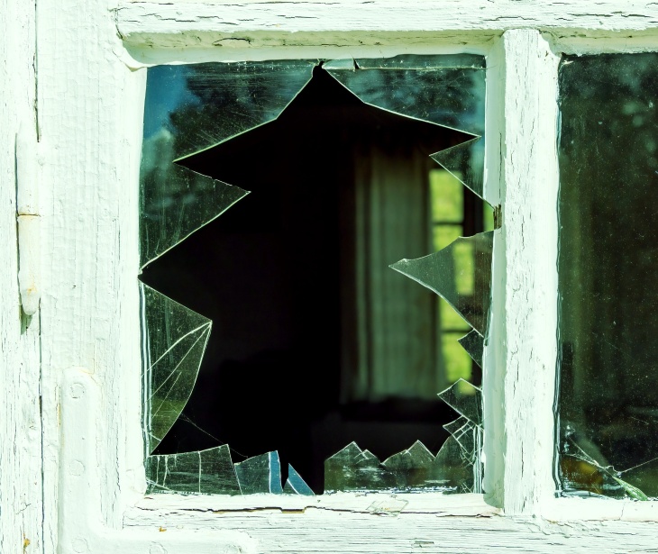 A pane of broken glass in a weathered white frame