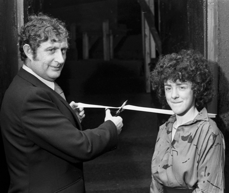 A black-and-white photograph of a man cutting the tape to officially open the new theatre. A woman stands next to him.