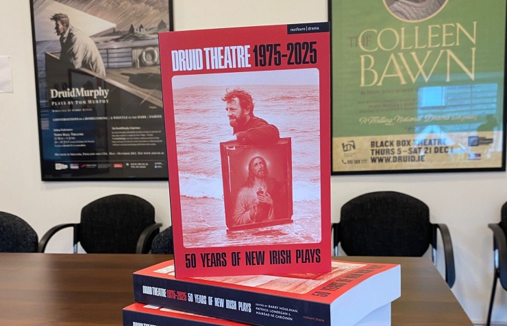 <p>A copy of the book stacked on some other copies of the book. Behind are some show posters.</p>