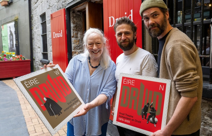 Druid Co-founder Marie Mullen and Druid Ensemble members Aaron Monaghan and Marty Rea photographed on Druid Lane holding large prints of Druid's special 50th anniversary stamps from An Post.